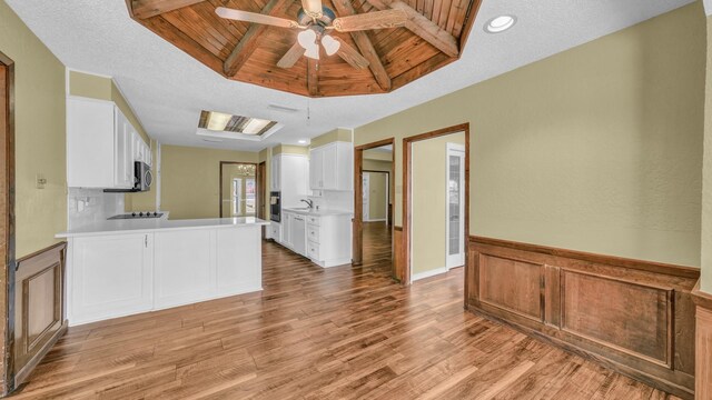 kitchen with white cabinets, wood ceiling, light wood-style flooring, appliances with stainless steel finishes, and light countertops