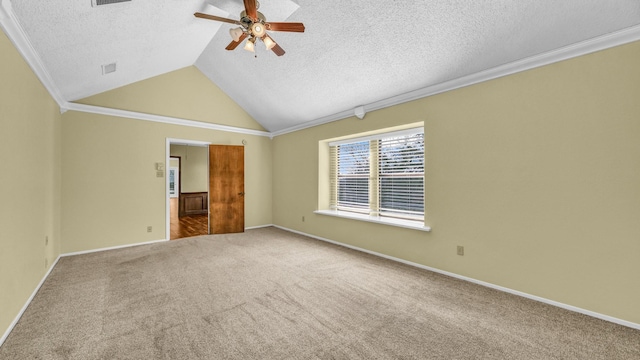 carpeted empty room with crown molding, vaulted ceiling, baseboards, and ceiling fan