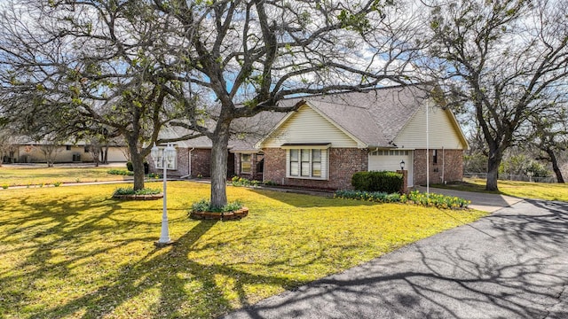 view of front of property with aphalt driveway, an attached garage, a shingled roof, brick siding, and a front yard