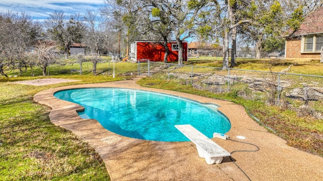 outdoor pool featuring an outdoor structure, fence, a diving board, and a yard