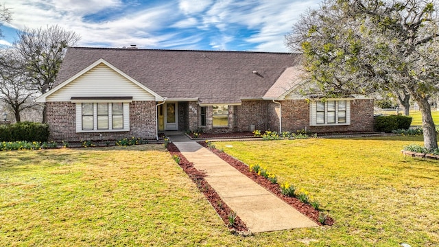 view of front of property with a front lawn, roof with shingles, and brick siding