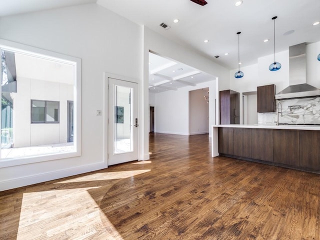 kitchen with dark wood-type flooring, light countertops, dark brown cabinetry, wall chimney range hood, and modern cabinets