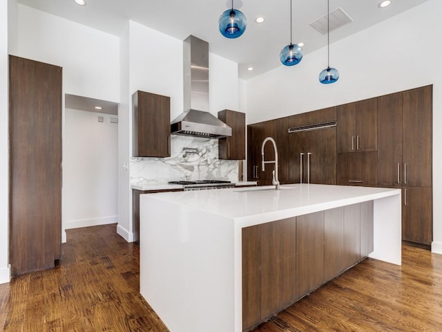 kitchen with a sink, dark wood-type flooring, modern cabinets, wall chimney exhaust hood, and built in fridge