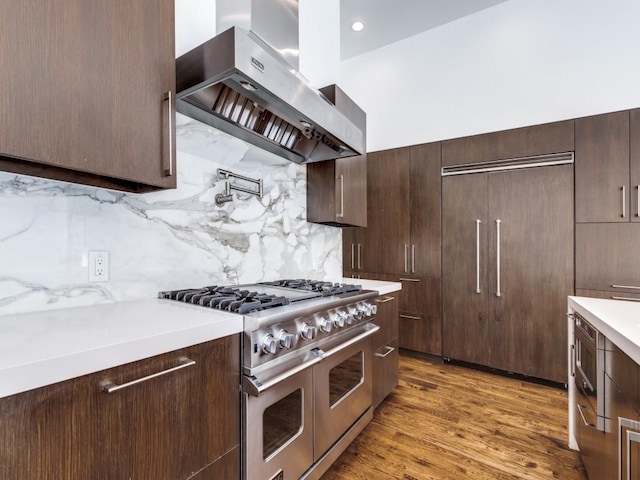 kitchen featuring dark brown cabinets, light countertops, extractor fan, and range with two ovens