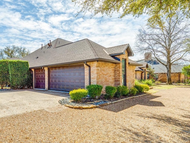 view of home's exterior featuring a garage, brick siding, concrete driveway, and a shingled roof