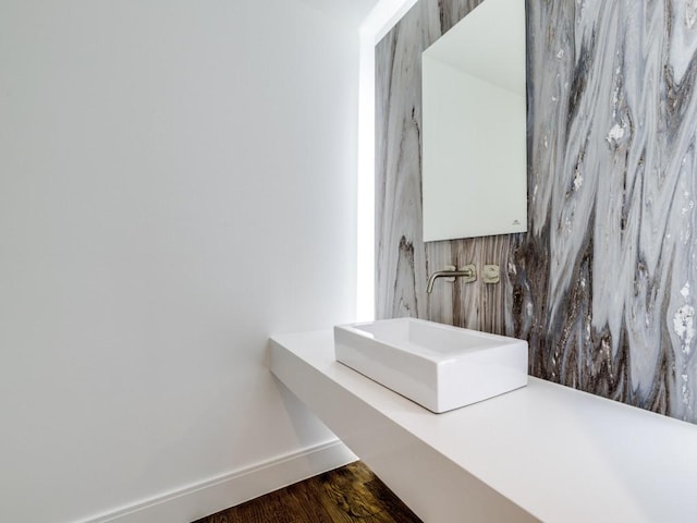 bathroom featuring wood finished floors, baseboards, and a sink