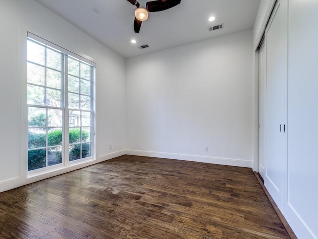 unfurnished room with visible vents, dark wood-type flooring, a healthy amount of sunlight, and ceiling fan