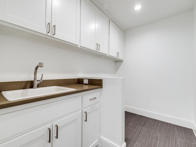 washroom with recessed lighting, baseboards, and a sink