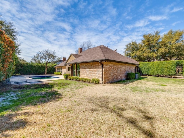 view of side of home featuring a fenced in pool, a chimney, a yard, and fence