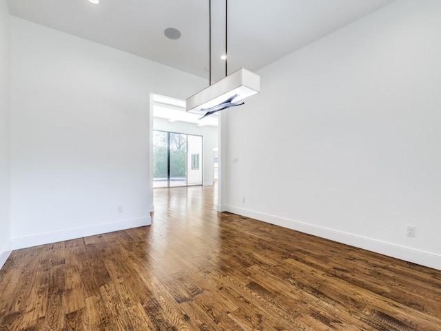 unfurnished dining area featuring baseboards and dark wood-style floors