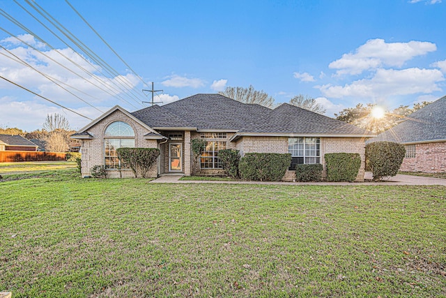 view of front of property with brick siding, a shingled roof, and a front yard