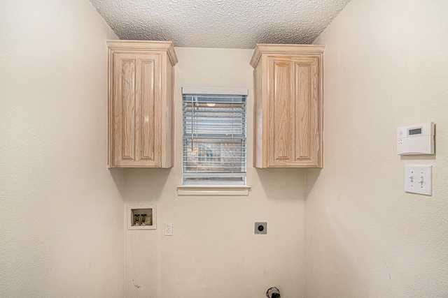 washroom with hookup for a washing machine, hookup for an electric dryer, cabinet space, and a textured ceiling