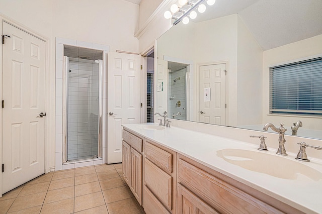 full bath featuring double vanity, a stall shower, tile patterned flooring, and a sink