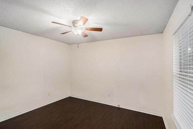 empty room with dark wood-style floors, ceiling fan, a textured ceiling, and baseboards