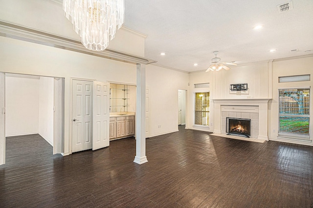 unfurnished living room with a wealth of natural light, visible vents, crown molding, and a fireplace