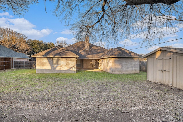 rear view of house with a storage unit, a yard, and brick siding