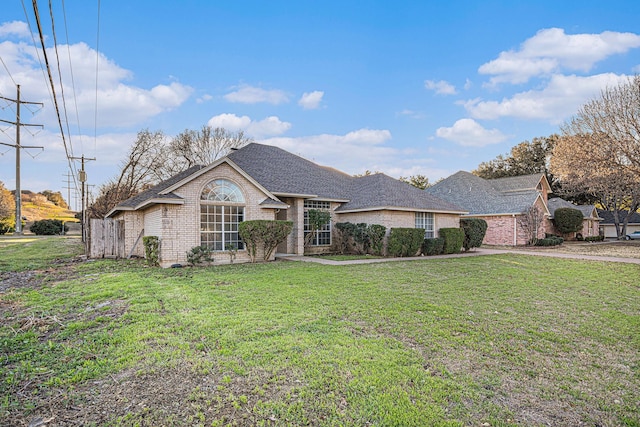 view of front of property featuring brick siding, a front lawn, and a shingled roof