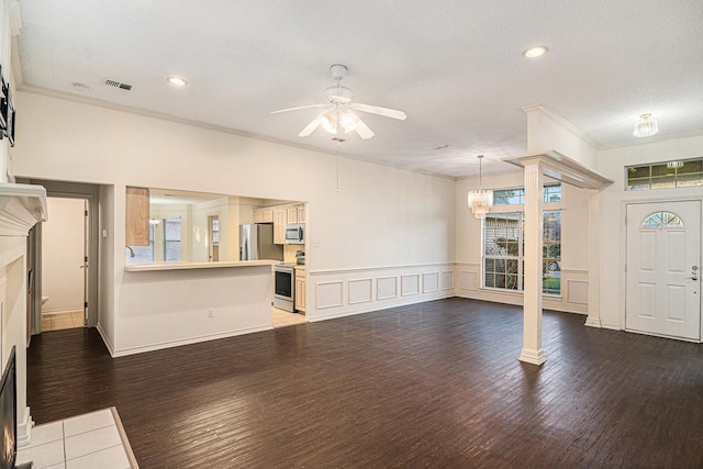 unfurnished living room with ceiling fan with notable chandelier, ornamental molding, wood finished floors, and visible vents