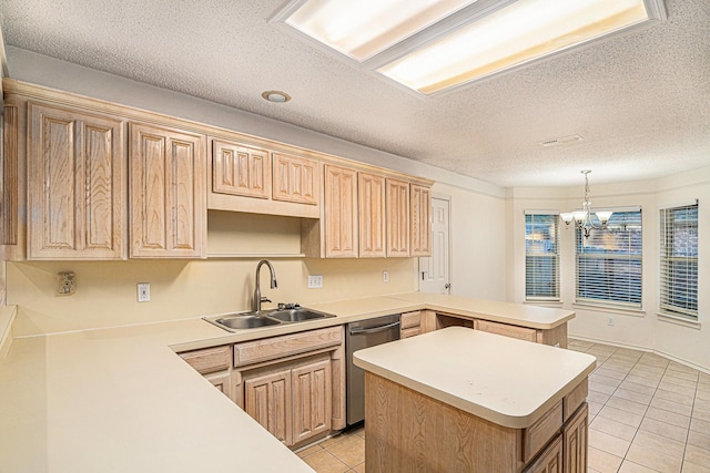 kitchen with a peninsula, stainless steel dishwasher, light countertops, and a sink