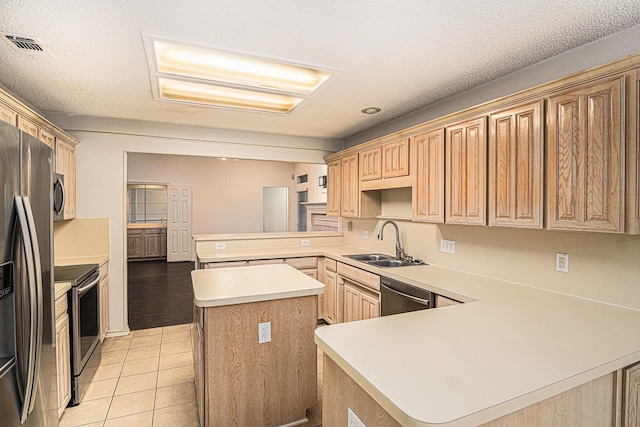 kitchen with visible vents, a kitchen island, appliances with stainless steel finishes, a peninsula, and a sink