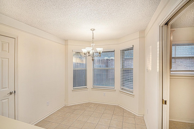 unfurnished dining area featuring a textured ceiling, light tile patterned flooring, baseboards, and an inviting chandelier