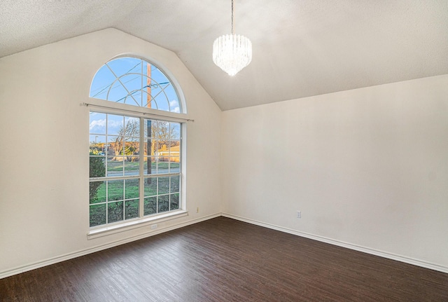 spare room with vaulted ceiling, a notable chandelier, dark wood finished floors, and baseboards