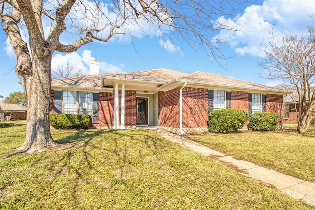 ranch-style home with a front yard, brick siding, and a chimney