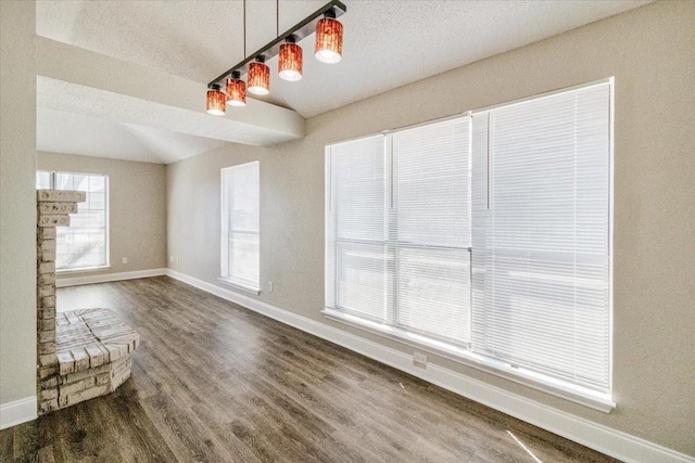 unfurnished living room featuring a textured ceiling, baseboards, and dark wood-type flooring