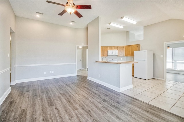 kitchen featuring light countertops, a ceiling fan, light wood-type flooring, white appliances, and baseboards