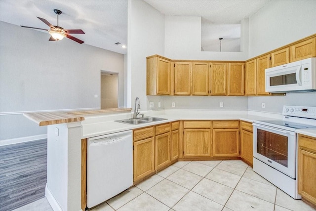 kitchen with white appliances, light countertops, a sink, and a peninsula