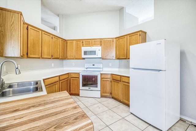 kitchen featuring white appliances, light countertops, a sink, and light tile patterned floors