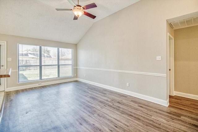 unfurnished room featuring ceiling fan, wood finished floors, visible vents, baseboards, and vaulted ceiling