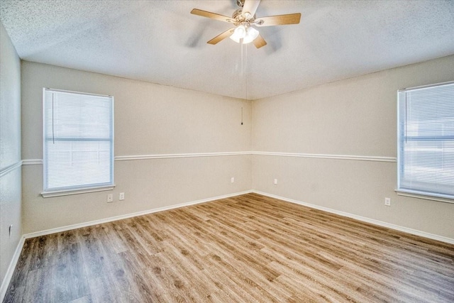 unfurnished room with a textured ceiling, wood finished floors, a ceiling fan, and baseboards