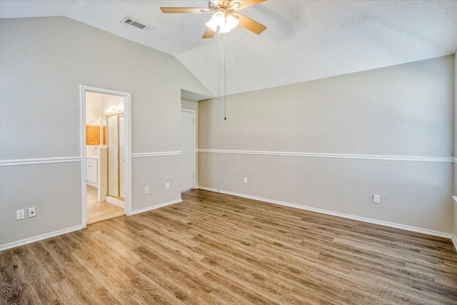 spare room with wood finished floors, visible vents, a ceiling fan, vaulted ceiling, and baseboards