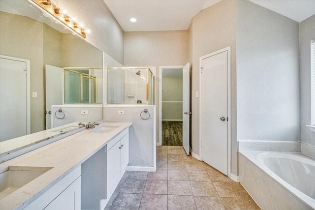 bathroom with a garden tub, a sink, a shower stall, and double vanity