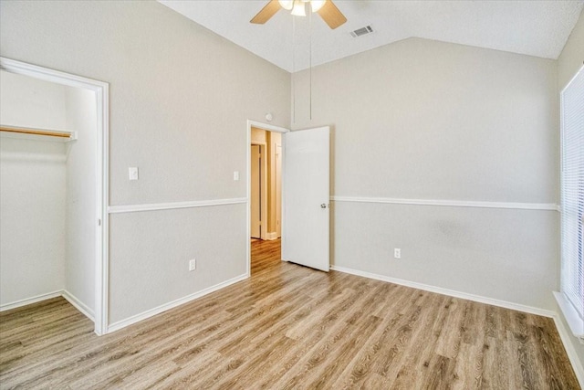 unfurnished bedroom with baseboards, visible vents, ceiling fan, wood finished floors, and vaulted ceiling