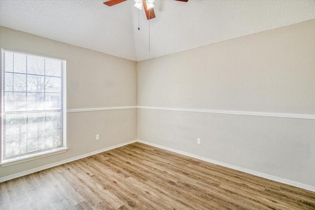 unfurnished room with lofted ceiling, ceiling fan, a textured ceiling, and wood finished floors