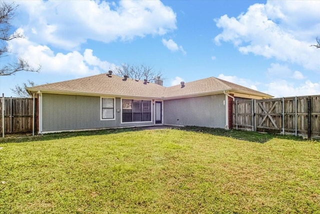 rear view of property featuring a lawn and a fenced backyard