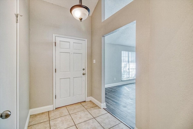 entryway featuring a textured ceiling, light tile patterned flooring, and baseboards