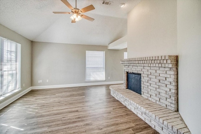 unfurnished living room with a fireplace, wood finished floors, visible vents, baseboards, and vaulted ceiling