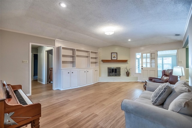 living room featuring visible vents, baseboards, light wood-style flooring, a textured ceiling, and a brick fireplace