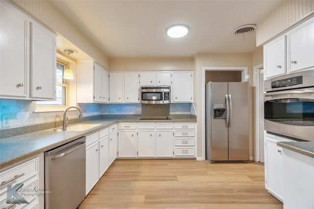 kitchen with light wood-style flooring, a sink, visible vents, white cabinetry, and appliances with stainless steel finishes