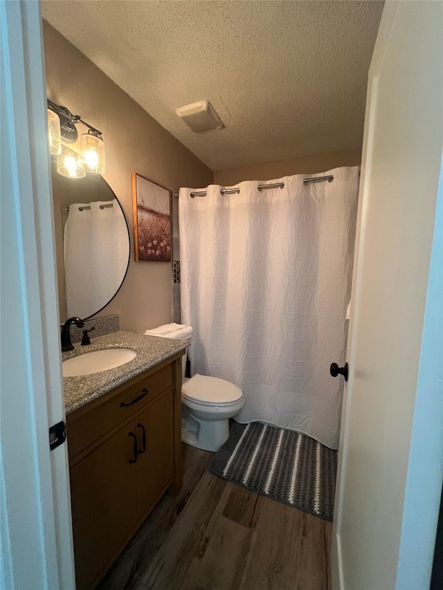 bathroom featuring a textured ceiling, toilet, a shower with shower curtain, wood finished floors, and vanity