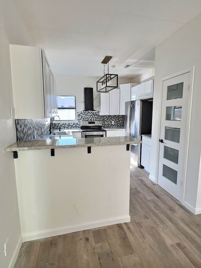 kitchen with stainless steel appliances, a peninsula, a sink, and light wood-style flooring