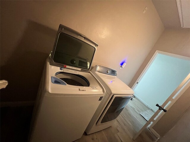 laundry area with laundry area, washer and clothes dryer, and wood finished floors