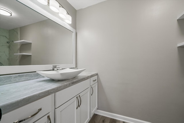 full bath featuring wood finished floors, walk in shower, vanity, and baseboards