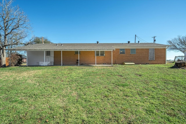 rear view of property with crawl space, brick siding, and a yard