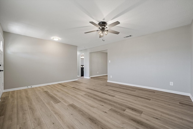 spare room featuring baseboards, light wood-type flooring, visible vents, and a ceiling fan