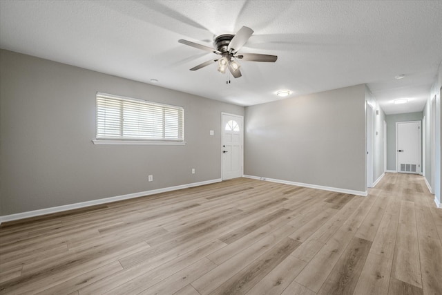 empty room with light wood-style flooring, visible vents, ceiling fan, and baseboards