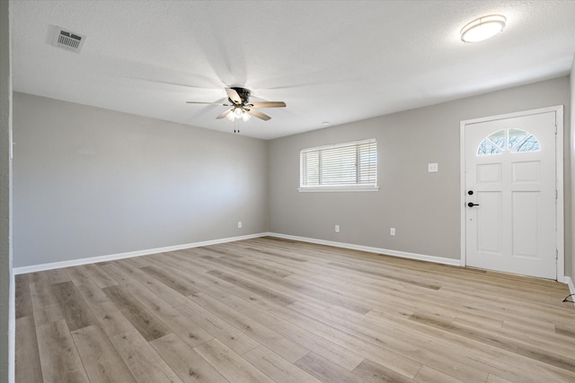 foyer featuring baseboards, visible vents, a ceiling fan, light wood-style flooring, and a textured ceiling